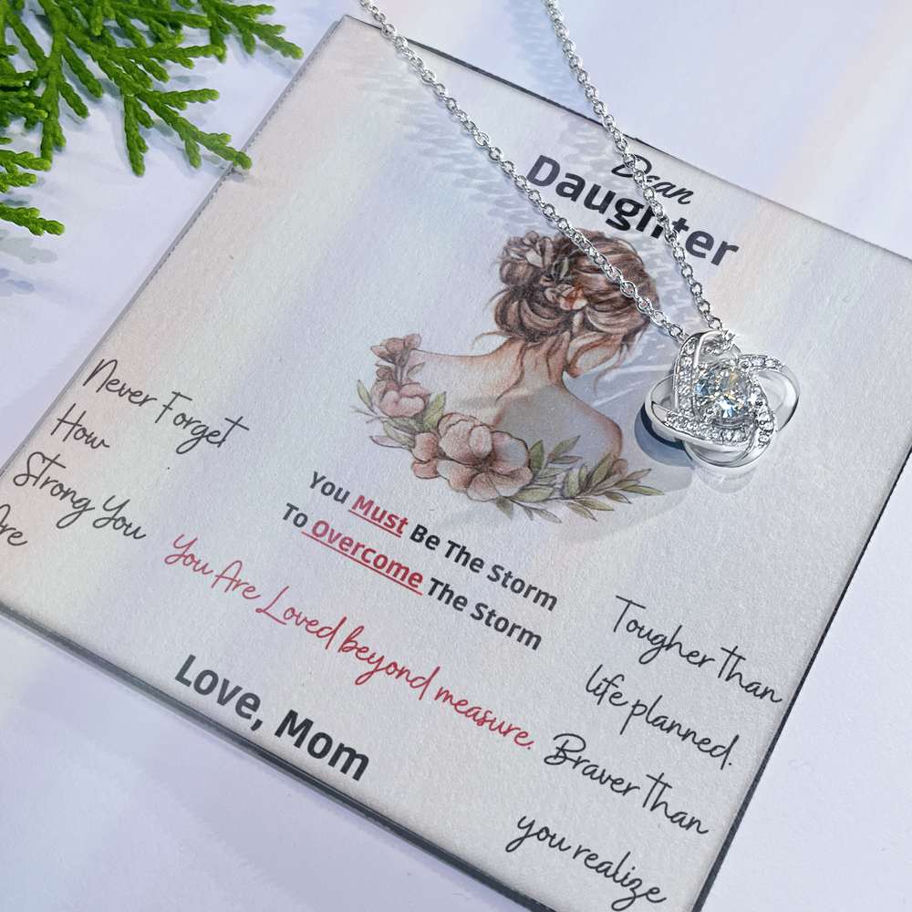 Framed as product alt text: Engraved mother to daughter necklace reading “Never forget how strong you are” with floral motif pendant
